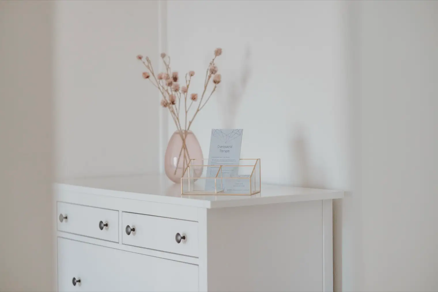 Kommode mit getrockneten Blumen und Informationskarten zur Craniosacral Therapie.